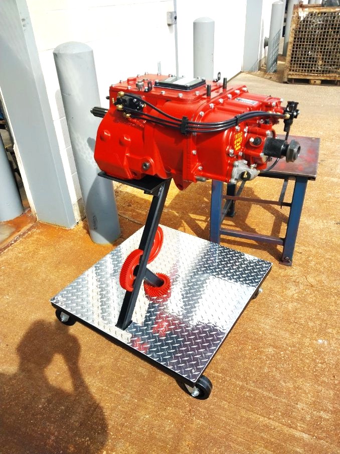Rolling diamond plate transmission display stand holding a rebuilt red heavy truck transmission