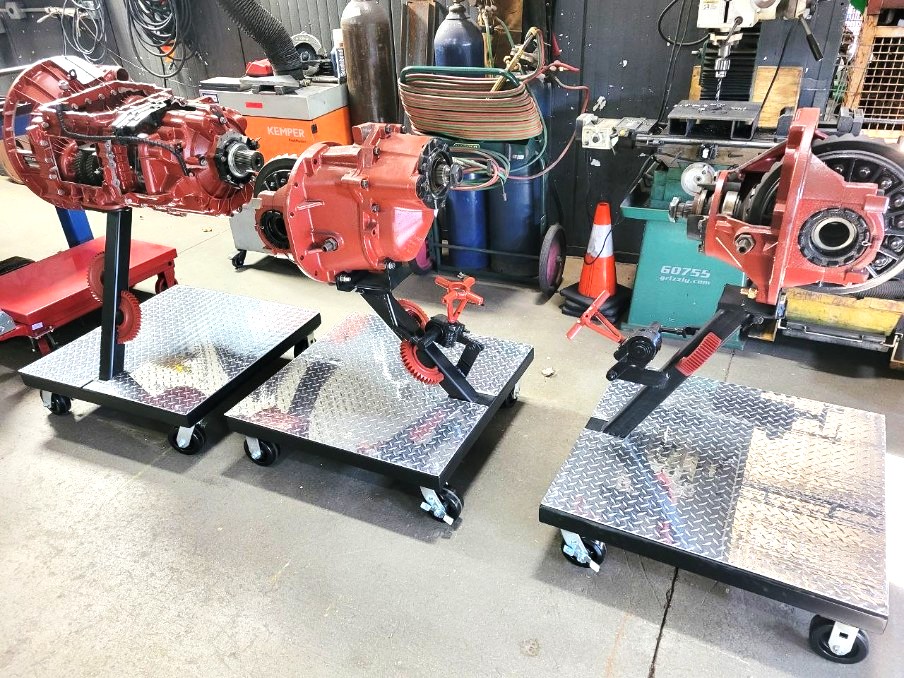 Three custom drivetrain rebuild carts with diamond plate decks and heavy-duty casters in the shop
