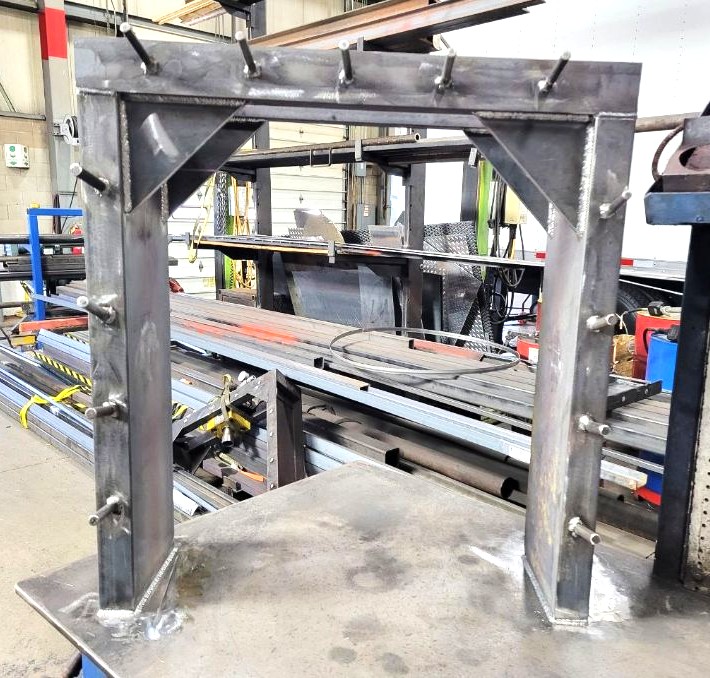 Fabricated steel gantry-style tool rack with gusseted corners and welded hanging pegs