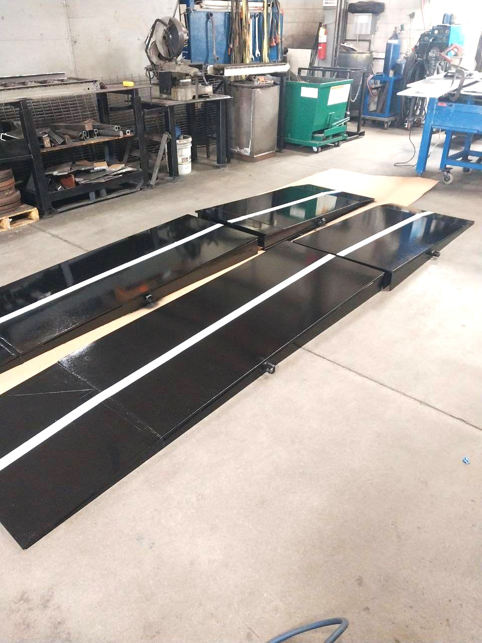 Set of gloss black steel loading ramps with white safety striping, finished in the shop