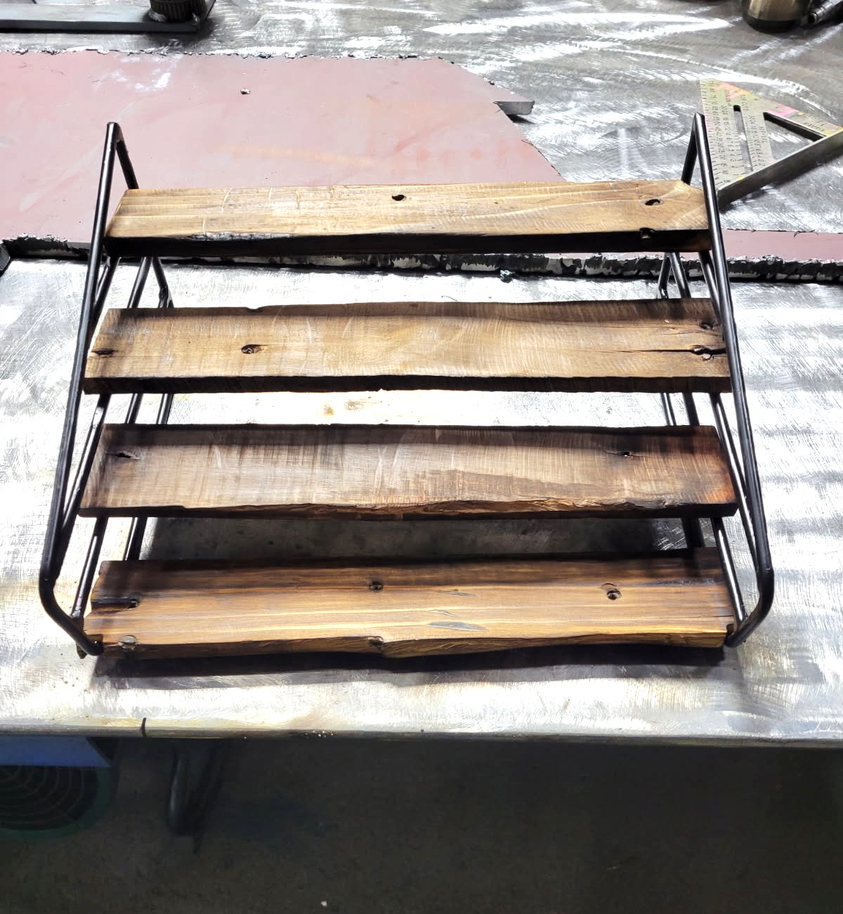 Four-tier steel rod display rack with rustic torched wood shelves