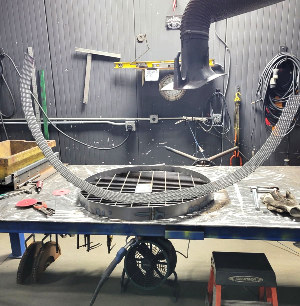 Custom round fire pit ring with steel grate and expanded metal arch fabricated on the shop table