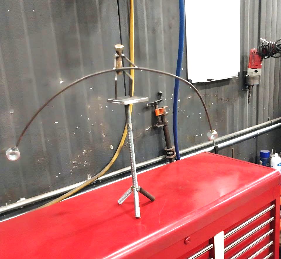 Steel arch fixture clamped and set up for a custom hand-forged stand