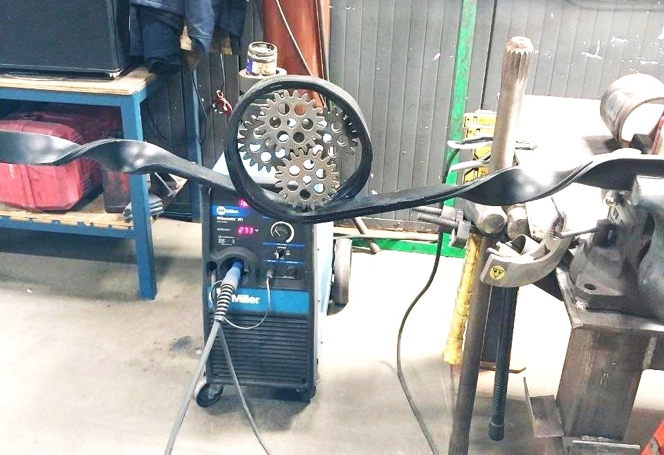 Decorative forged steel scrollwork with a cut gear centerpiece formed at the workbench