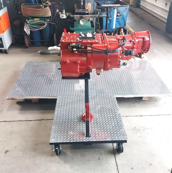 Diamond plate rolling stand supporting a rebuilt transmission and transfer assembly