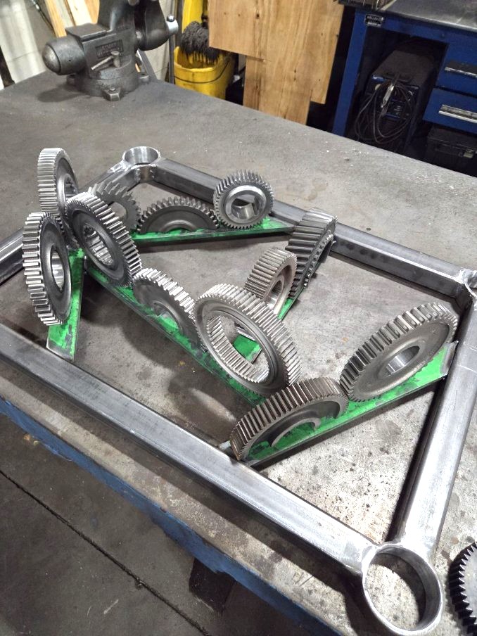 Steel frame art piece in progress with transmission gears arranged and welded in place