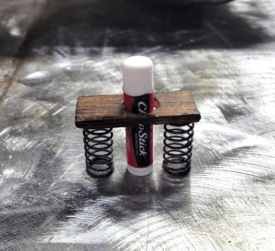 Miniature welded shop-art holder built from coil springs and reclaimed wood