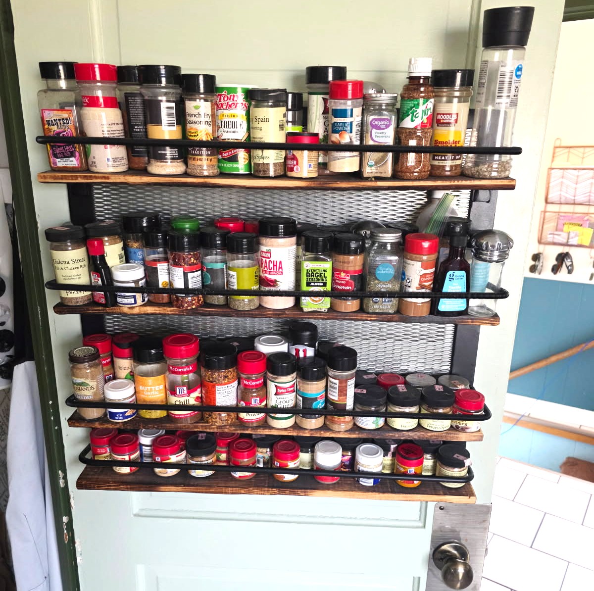 Custom four-tier steel and wood spice rack mounted on a pantry door