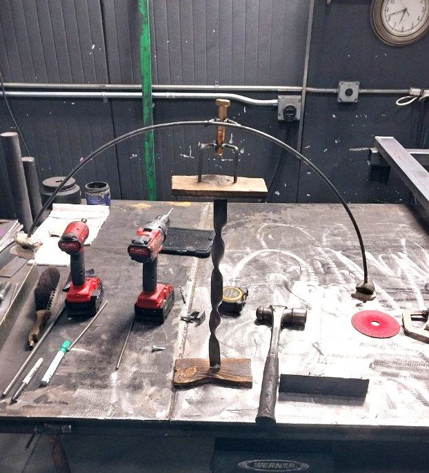 Hand-twisted steel shepherd hook stand in progress on the fabrication table