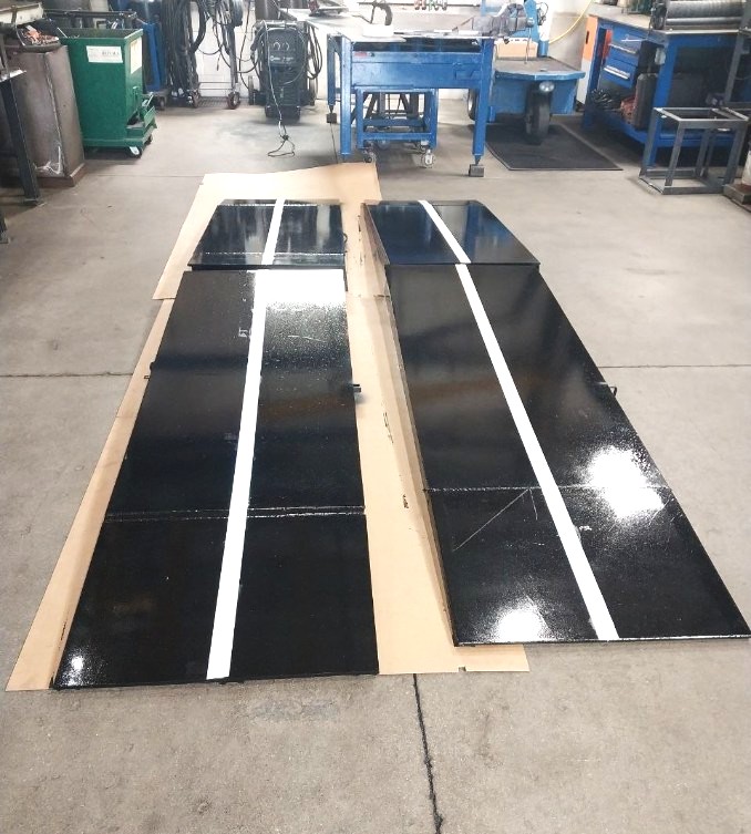 Freshly painted black steel ramp sections with reflective white stripe detail