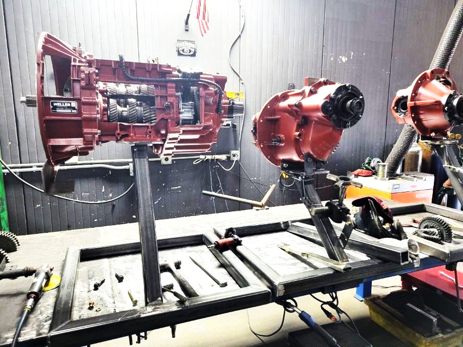 Custom welded transmission and differential repair stands supporting rebuilt drivetrain components