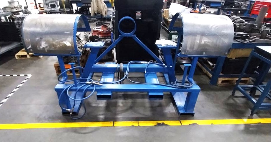 Custom blue steel transmission teardown and assembly fixture with hydraulic lines and roller cradles